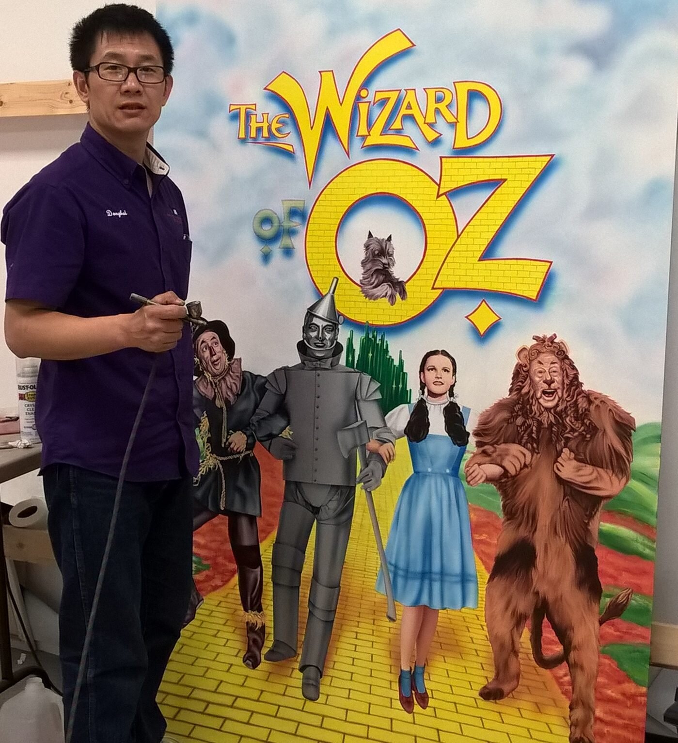 Artist Dongbai Tang beside one of his hand-painted murals